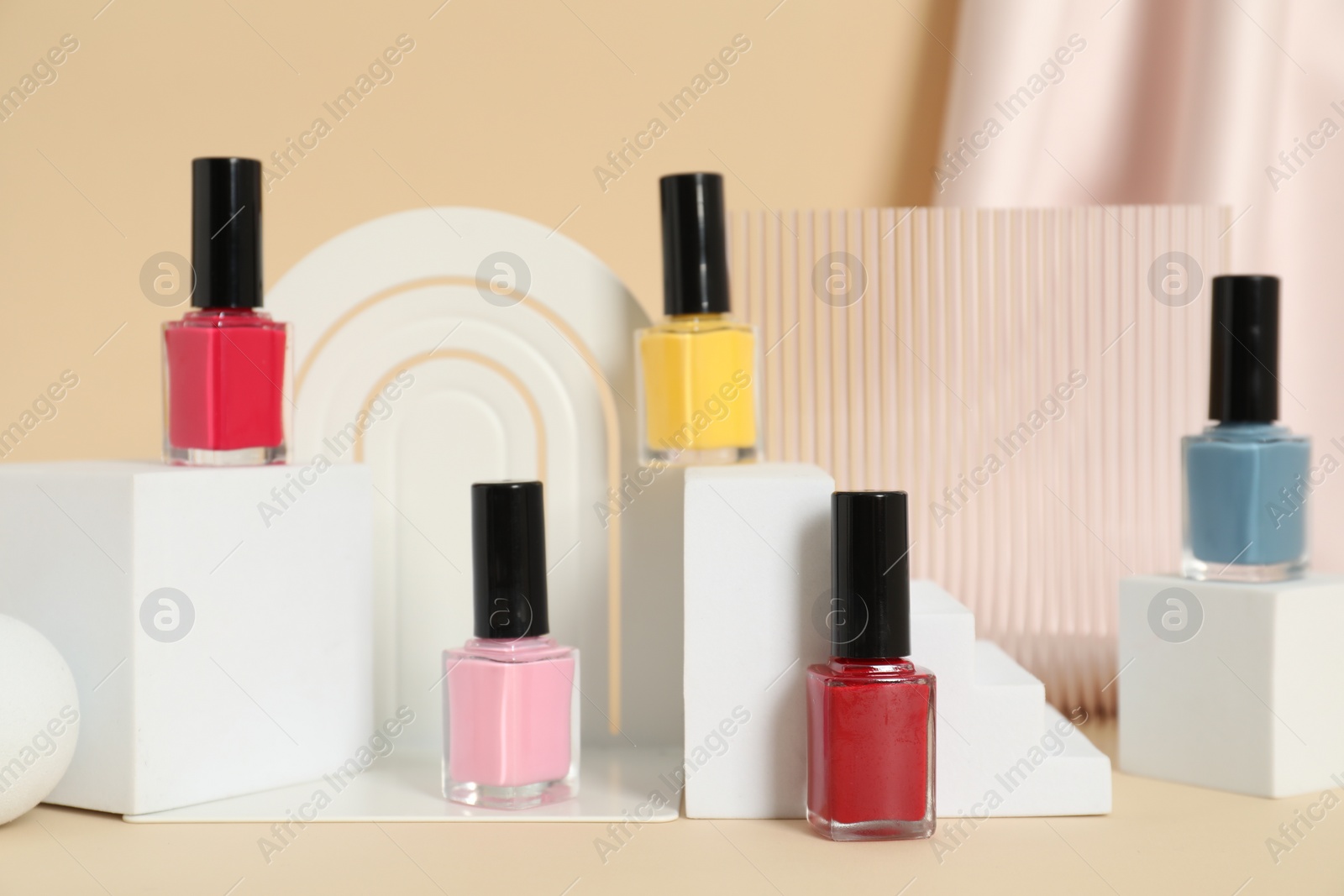 Photo of Stylish presentation of nail polishes on beige background