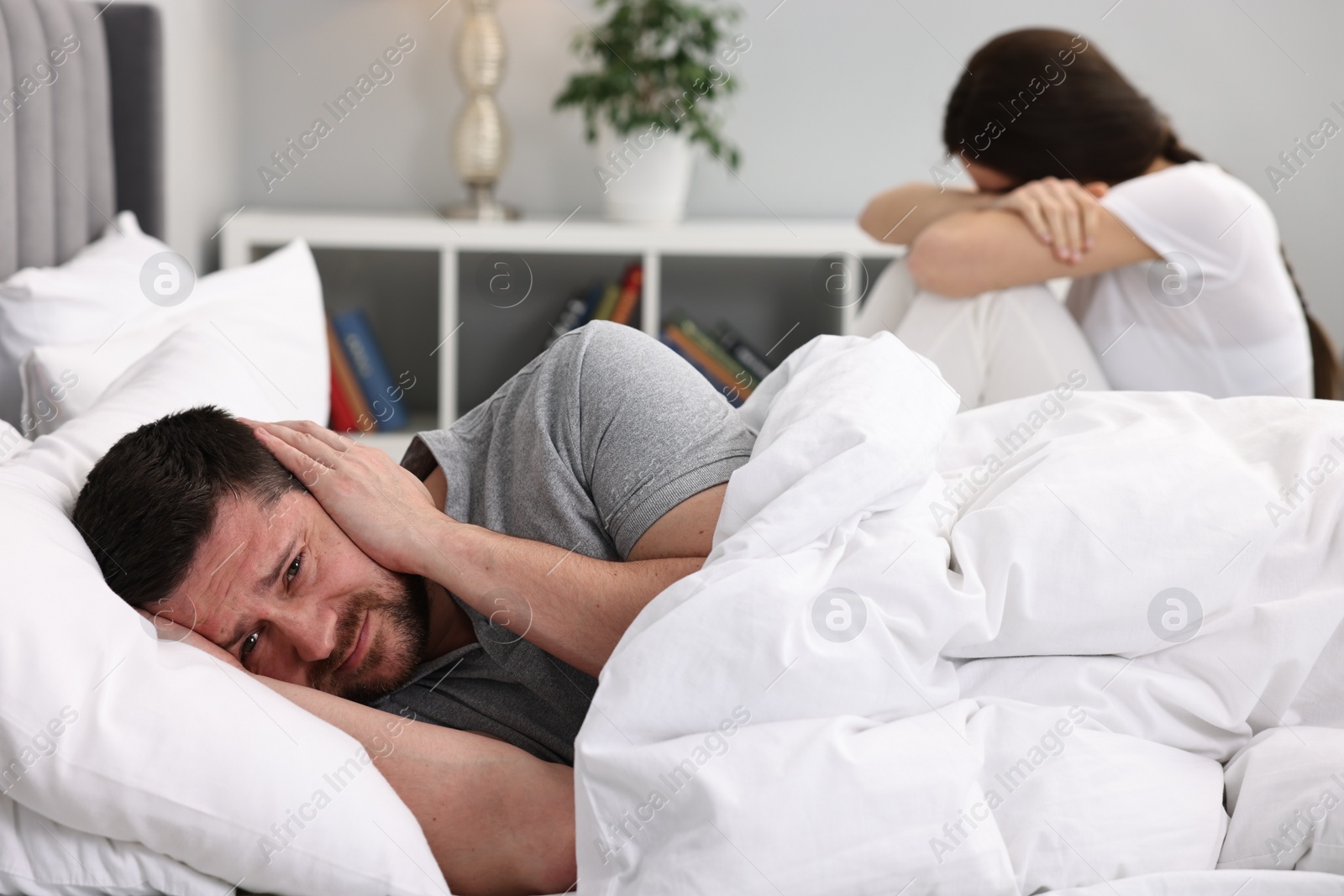 Photo of Offended couple ignoring each other after quarrel in bedroom, selective focus. Relationship problems