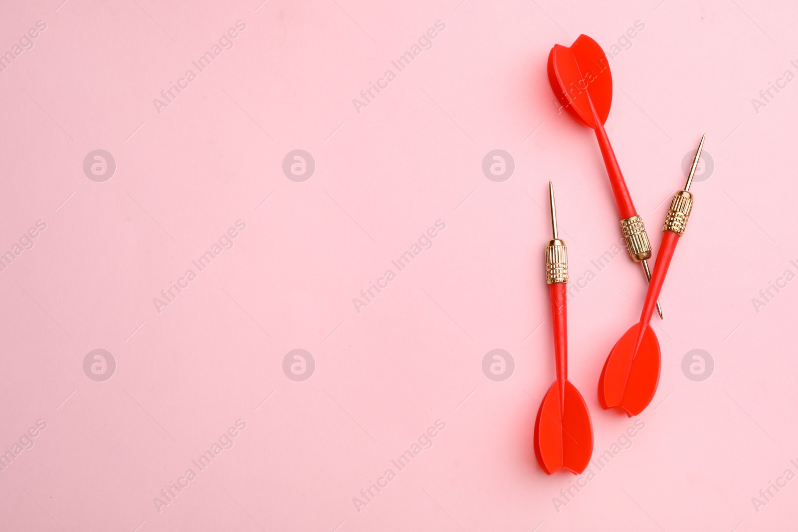 Photo of Red dart arrows on pink background, flat lay with space for text