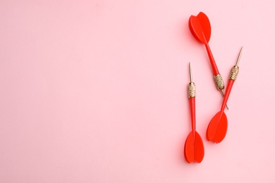 Photo of Red dart arrows on pink background, flat lay with space for text