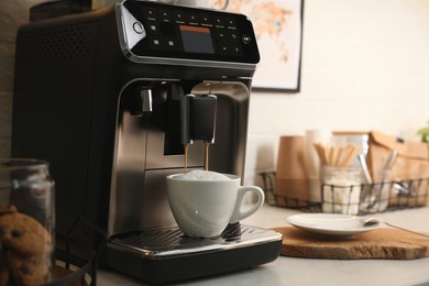 Photo of Modern coffee machine making cappuccino in office kitchen, space for text