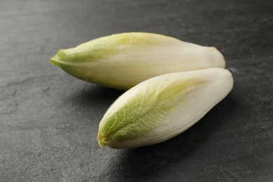 Photo of Fresh raw Belgian endives (chicory) on black table