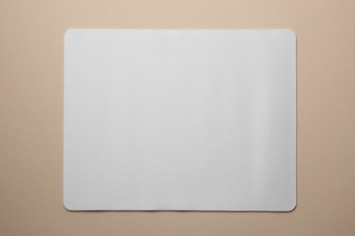 One mouse pad on beige background, top view. Space for text