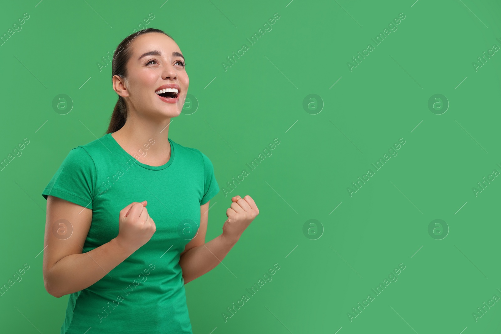 Photo of Happy sports fan celebrating on green background, space for text