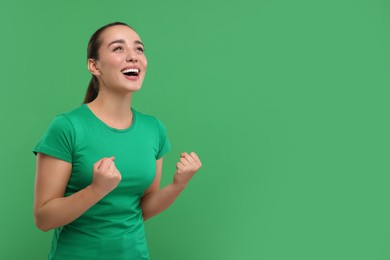Happy sports fan celebrating on green background, space for text
