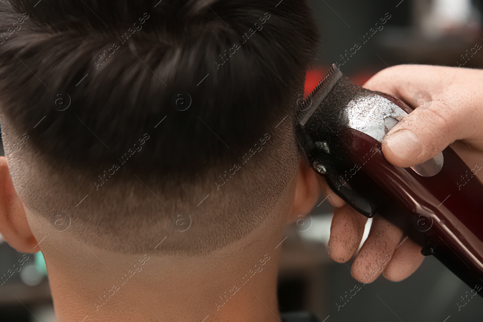 Photo of Professional barber making stylish haircut in salon, closeup