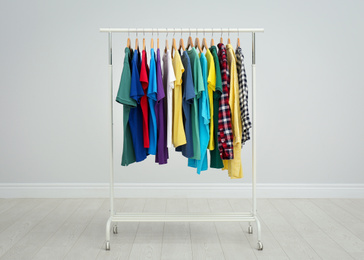 Photo of Rack with bright stylish clothes in room