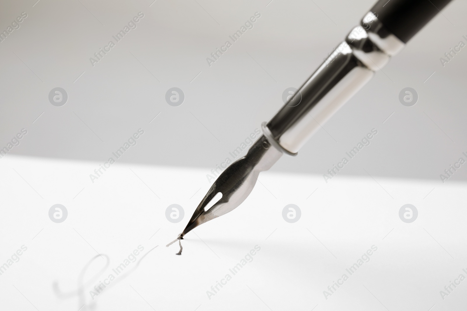 Photo of Signing on sheet of paper with fountain pen against light grey background, closeup. Space for text