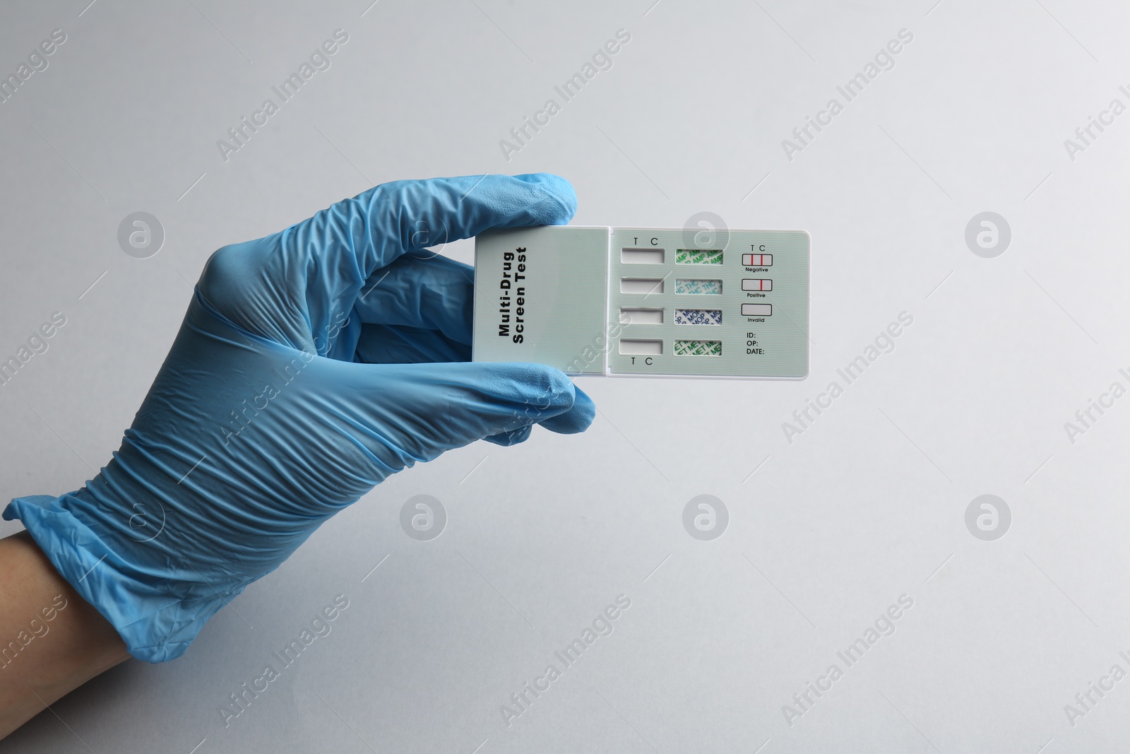 Photo of Doctor holding multi-drug screen test on light grey background, closeup