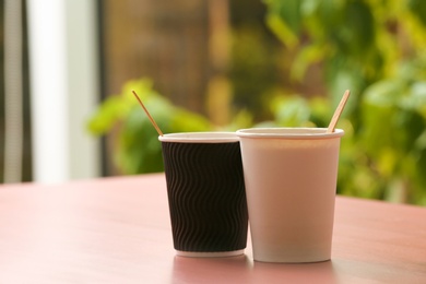 Cardboard cups of coffee on table against blurred background. Space for text