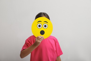 Photo of Little girl covering face with shocked emoji on white background