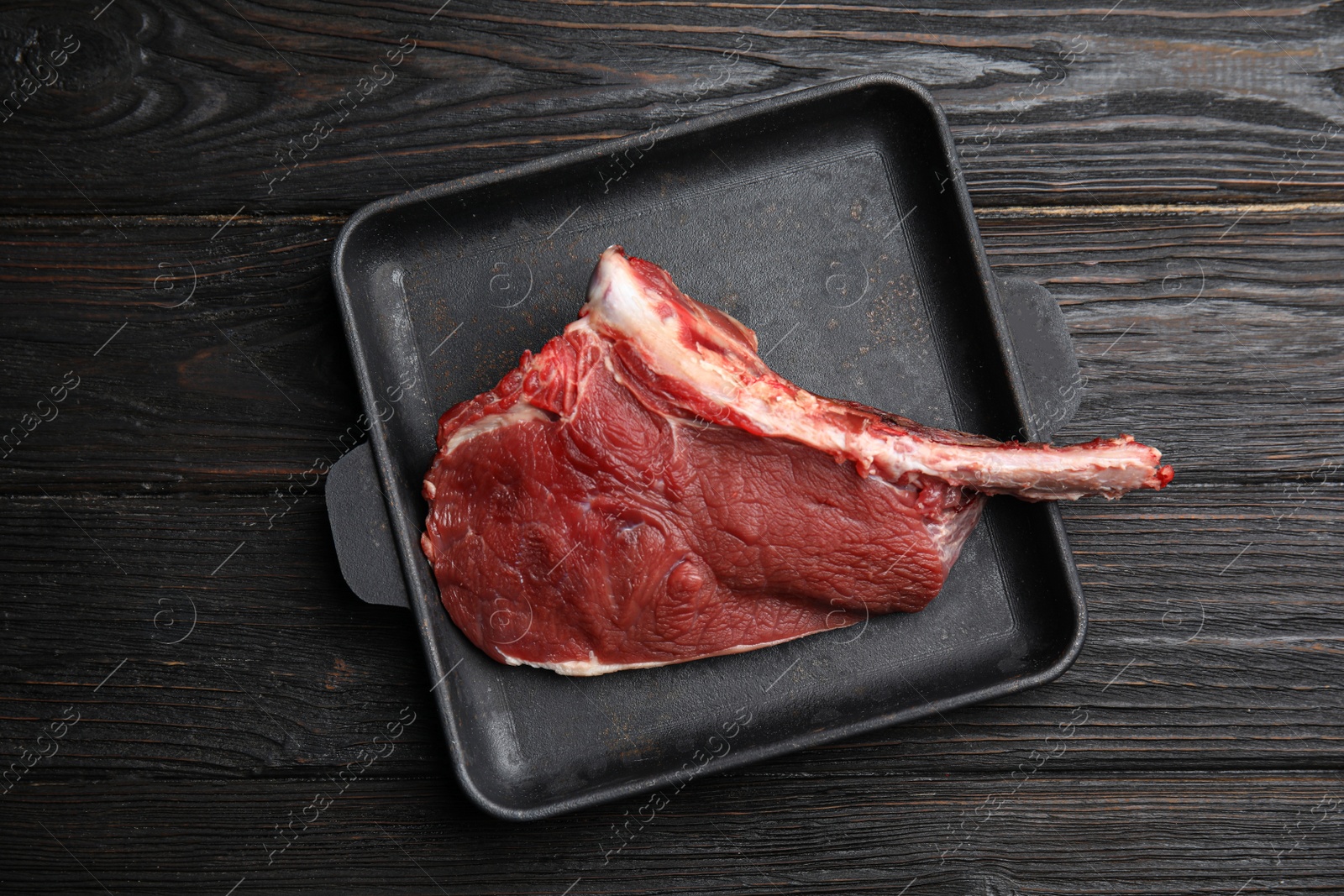 Photo of Fresh raw beef cut in baking dish on wooden table, top view