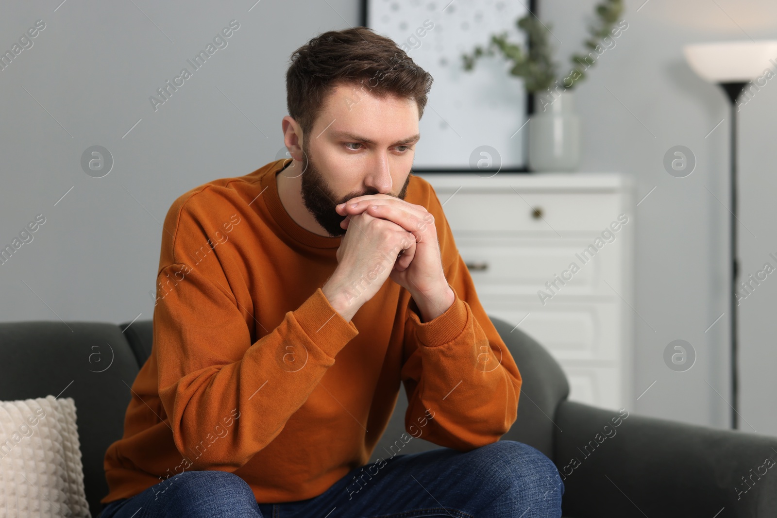 Photo of Overwhelmed man sitting on sofa at home