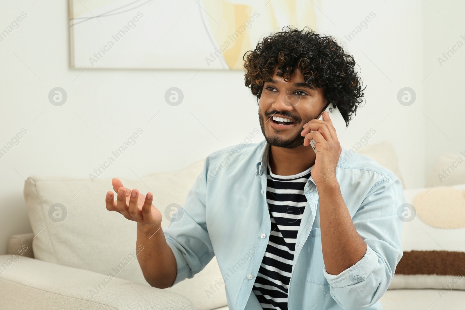 Photo of Handsome smiling man taking on smartphone in room