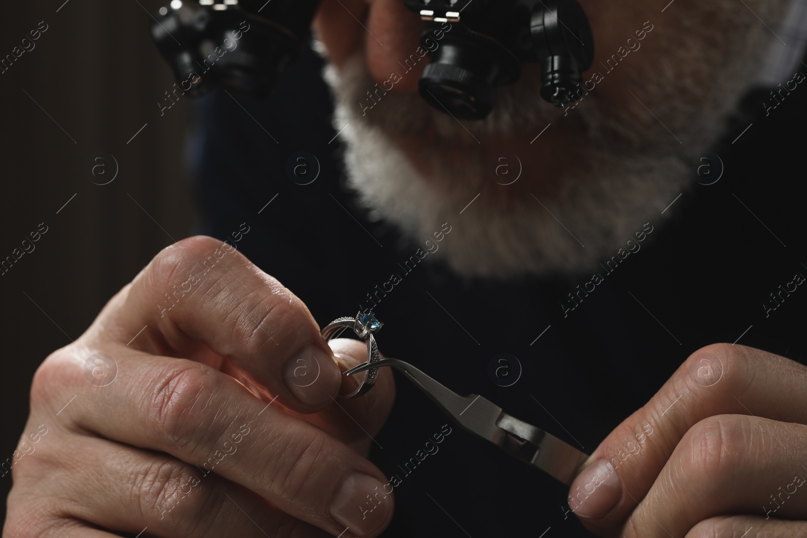 Photo of Professional jeweler working with ring on dark background, closeup