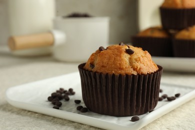 Photo of Delicious sweet muffin with chocolate chips on light textured table, closeup. Space for text