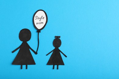 Being single mother concept. Woman with her child made of paper on light blue background, flat lay and space for text