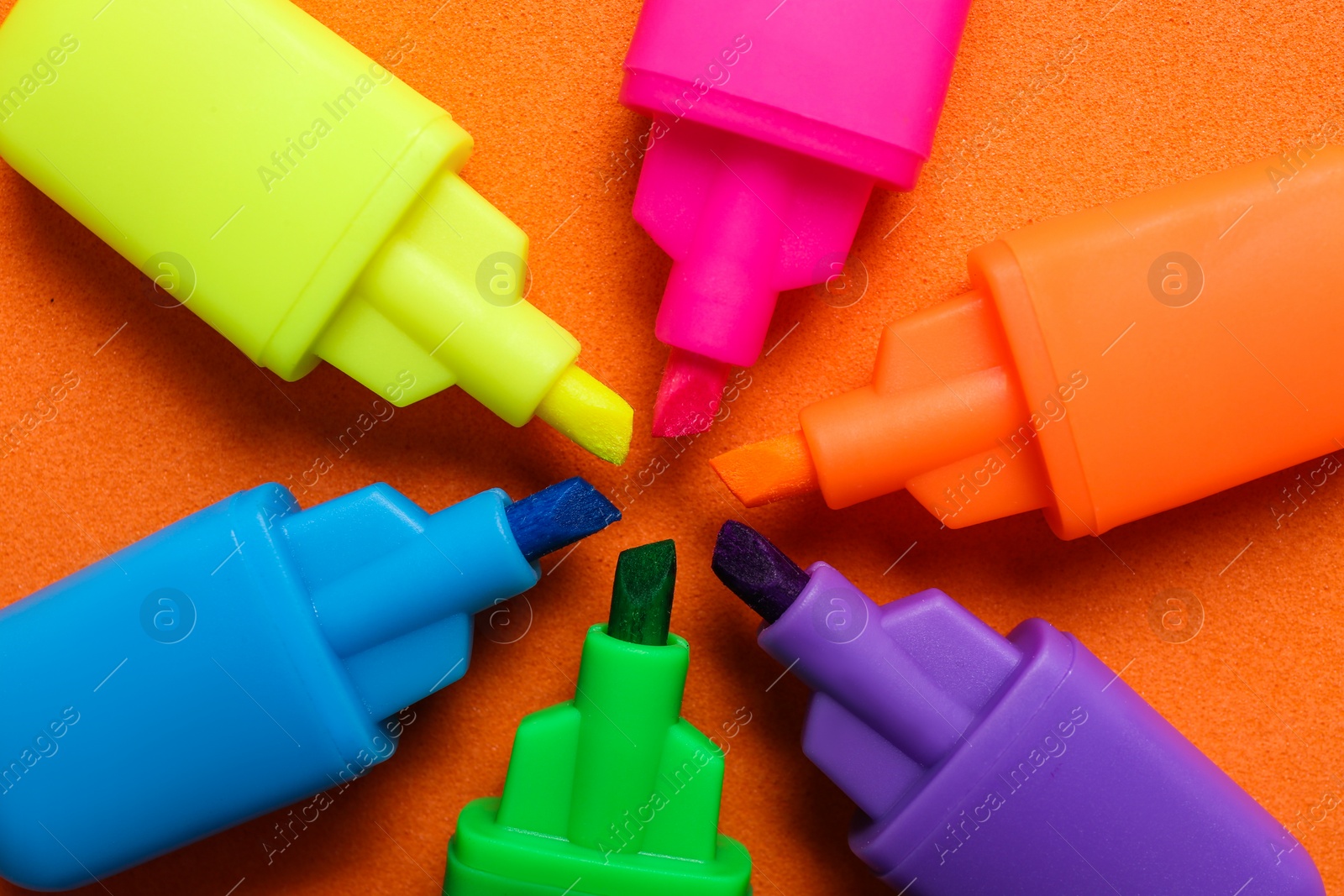 Photo of Set of highlighters on orange background, flat lay