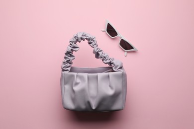 Photo of Stylish woman's bag and sunglasses on pink background, flat lay