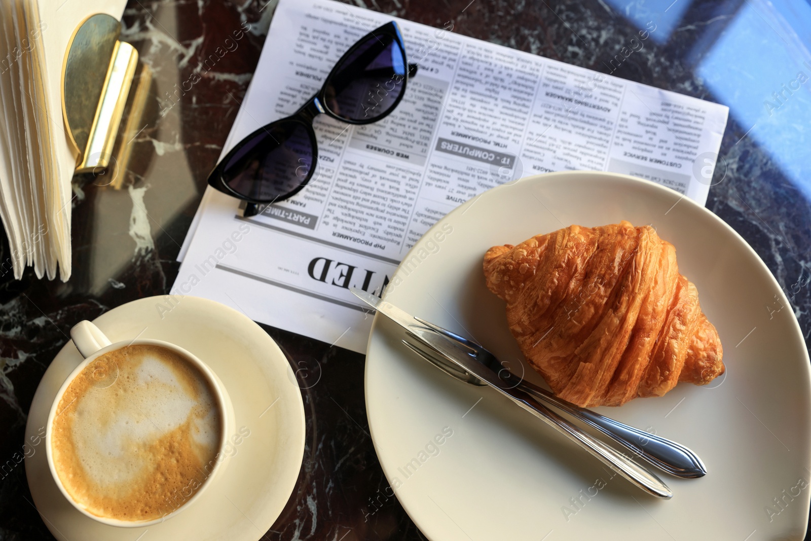 Photo of Flat lay composition with tasty croissant and cup of aromatic coffee on black table in cafeteria