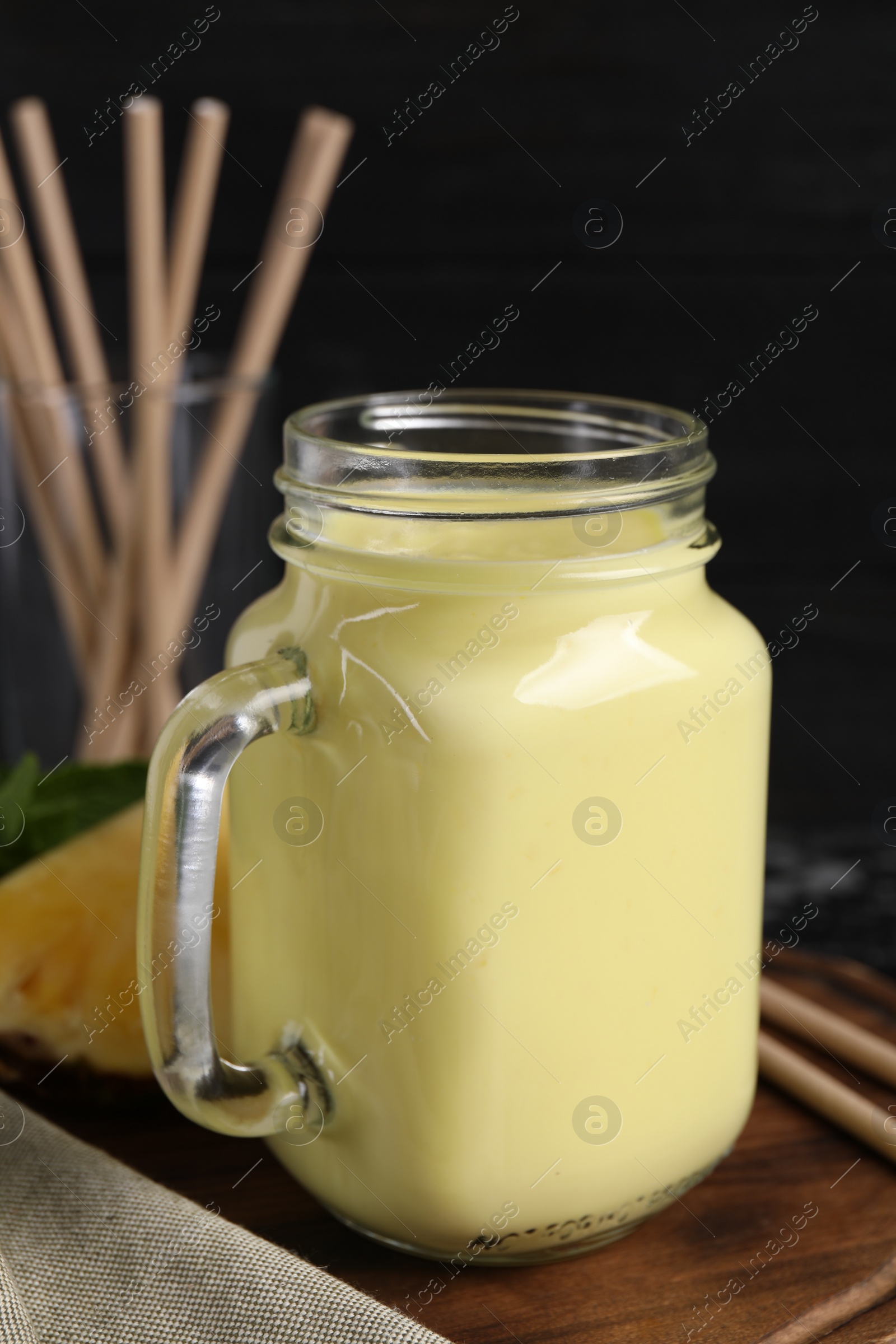 Photo of Tasty pineapple smoothie in mason jar on table, closeup