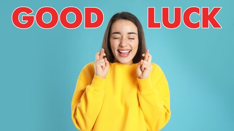 Woman with crossed fingers on light blue background. Good luck superstition