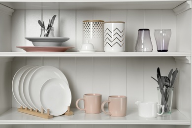 Photo of White shelving unit with set of dishware