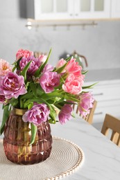 Photo of Beautiful bouquet of colorful tulip flowers on white marble table in kitchen