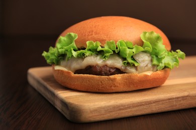 Photo of One tasty cheeseburger on wooden table, closeup