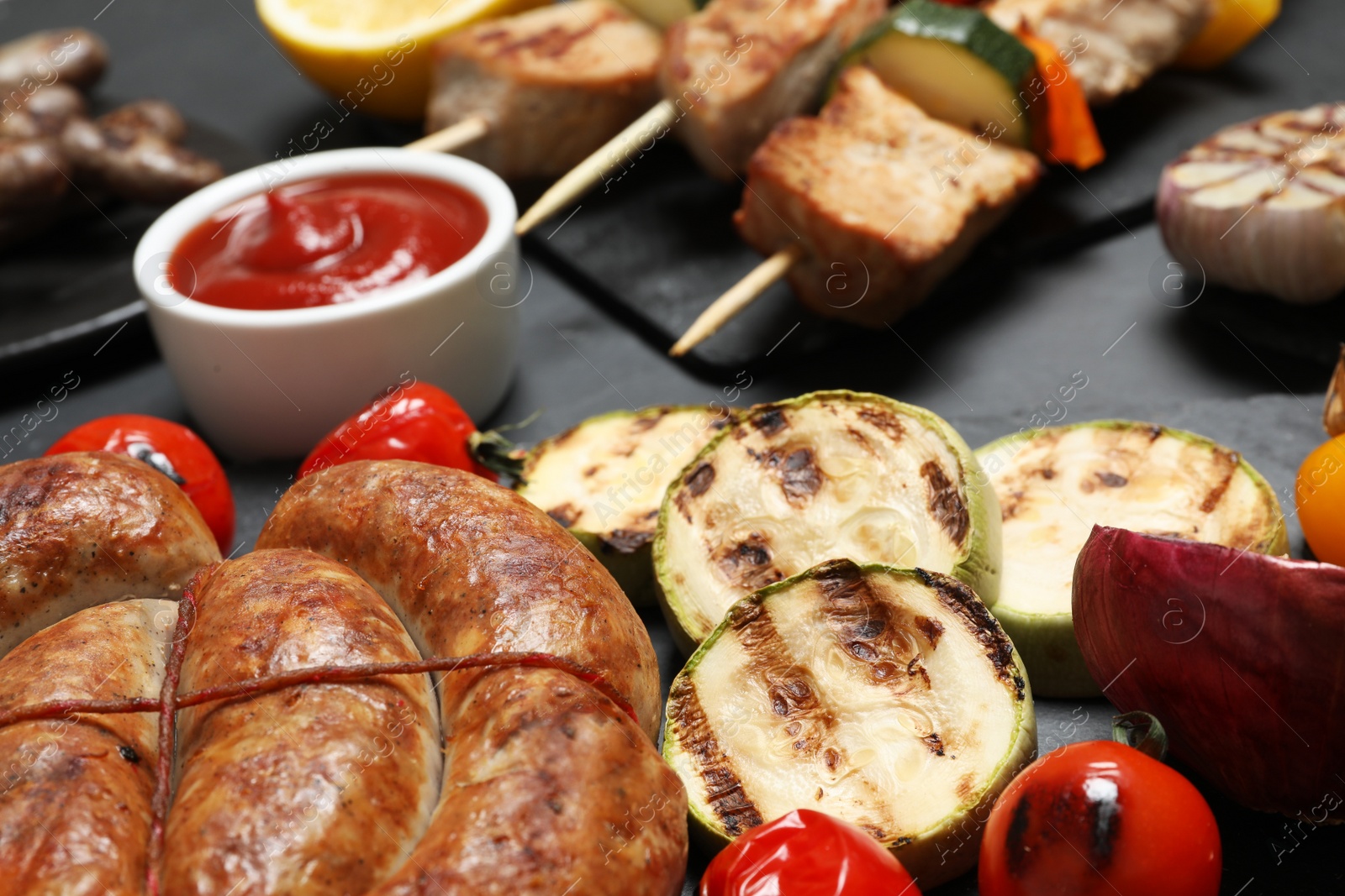 Photo of Barbecued meat and vegetables on grey table, closeup