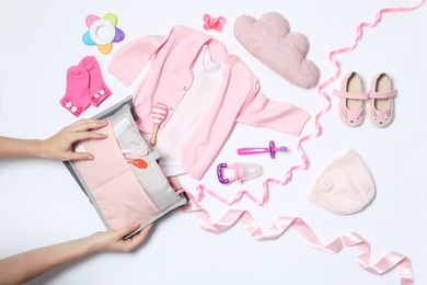 Woman with maternity bag and baby accessories on white background, top view