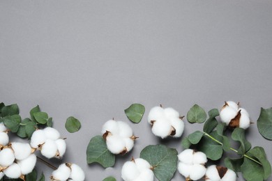 Photo of Cotton flowers and eucalyptus leaves on grey background, flat lay. Space for text