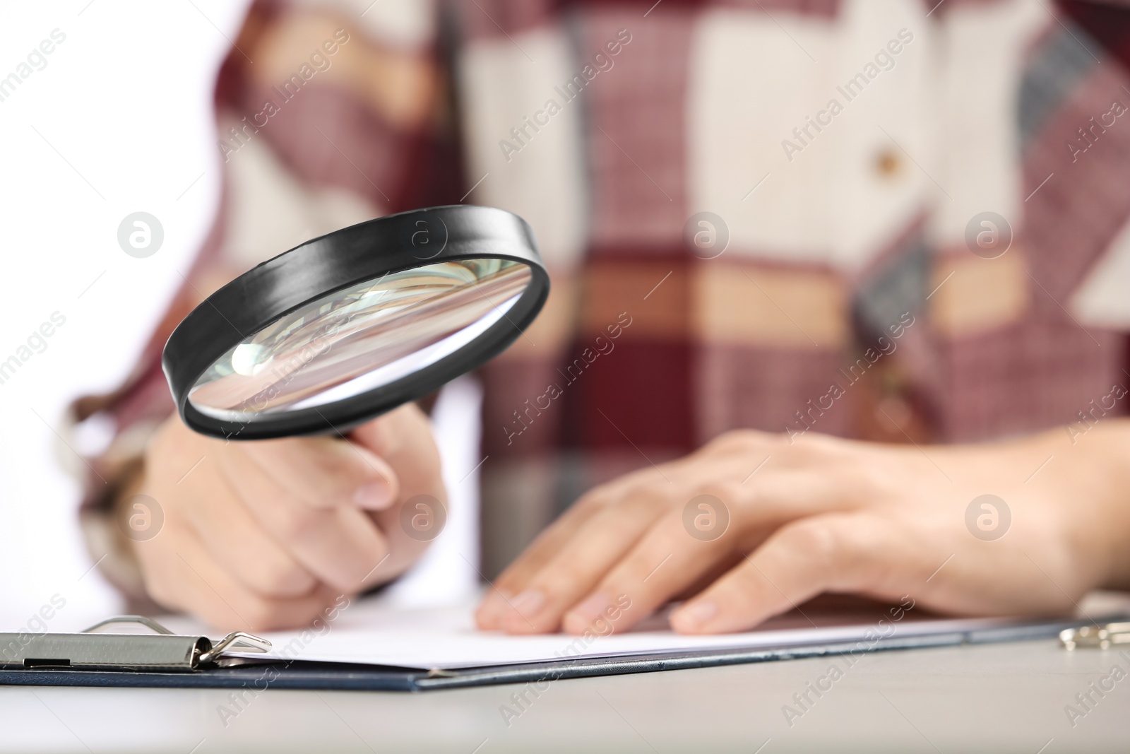 Photo of Woman using magnifying glass at table, closeup