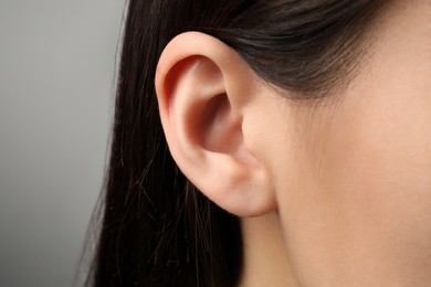 Photo of Closeup view of woman against light grey background, focus on ear