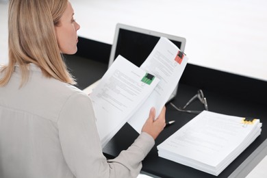 Photo of Businesswoman working with documents at dark table in office, closeup