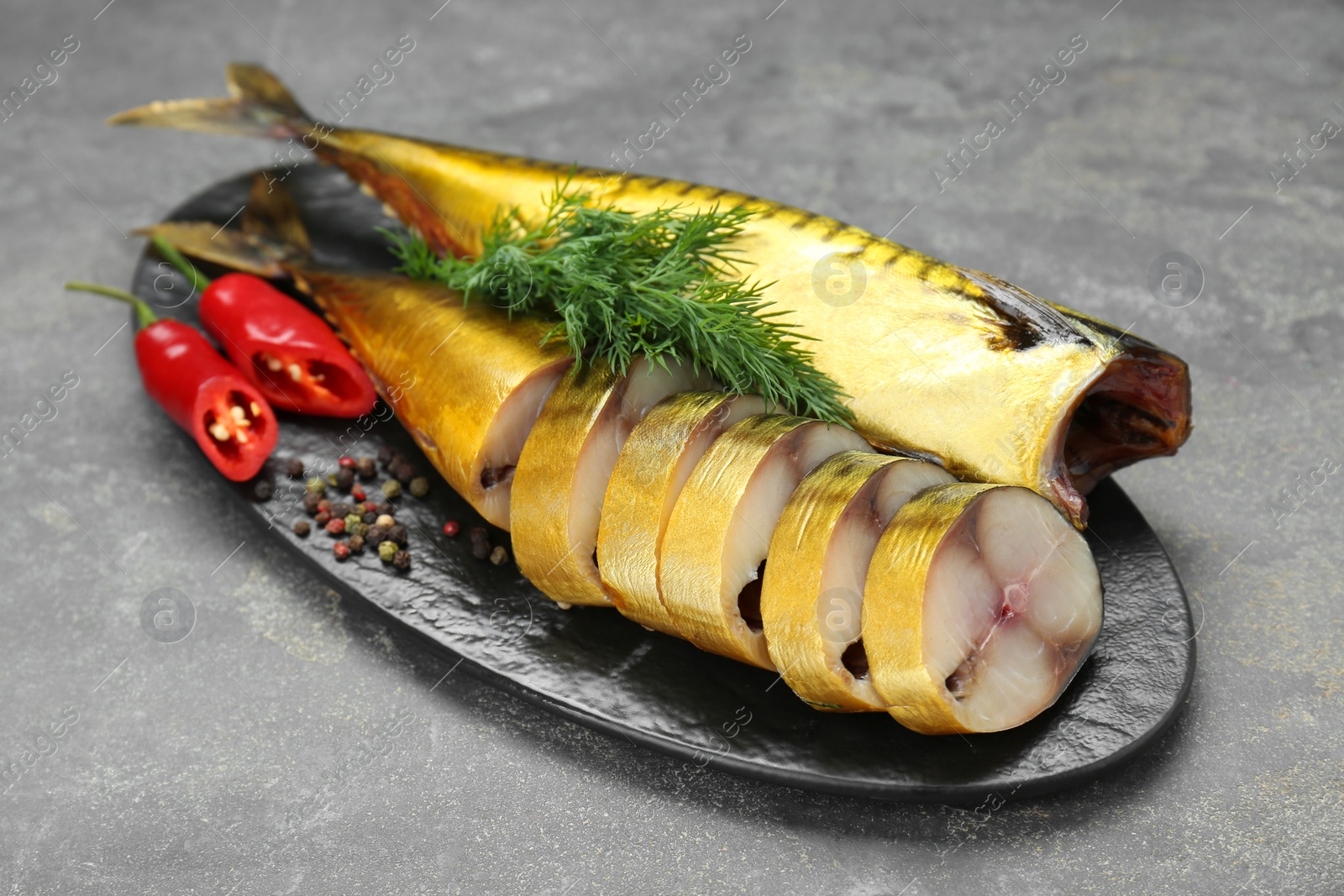 Photo of Delicious smoked mackerels with pepper, dill and spices on dark grey table, closeup