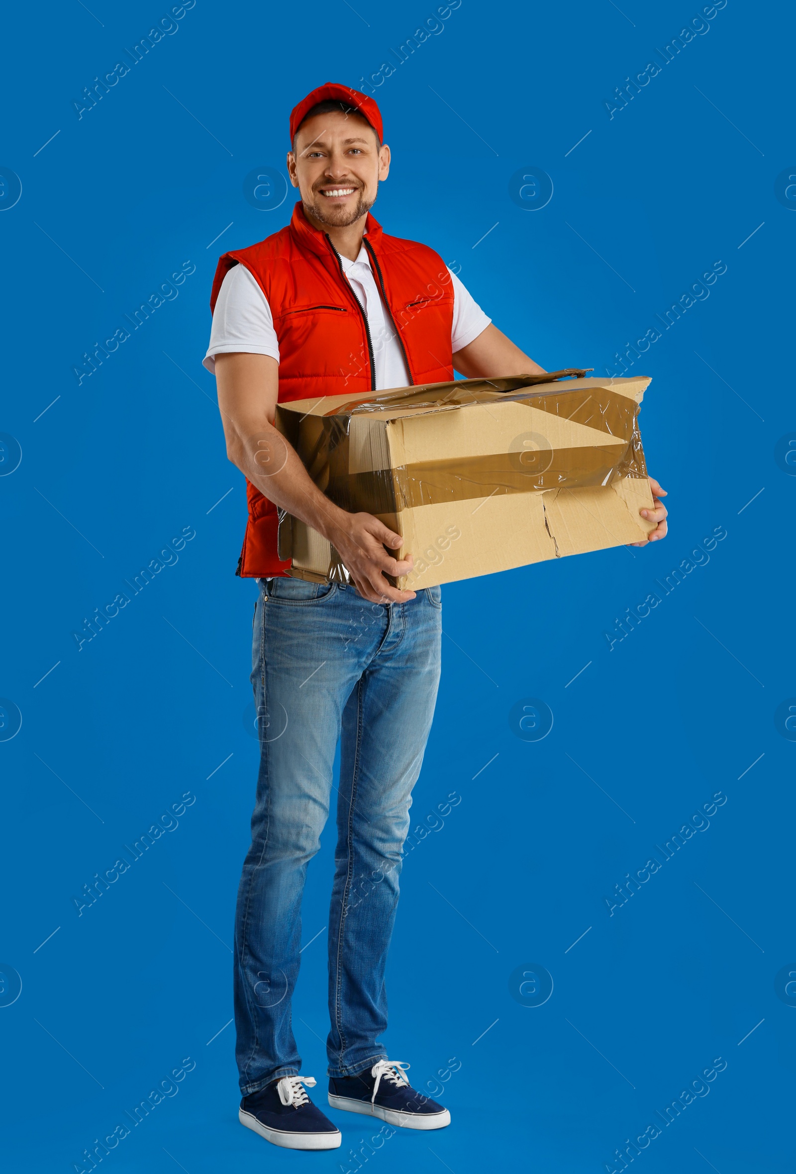 Photo of Courier with damaged cardboard box on blue background. Poor quality delivery service