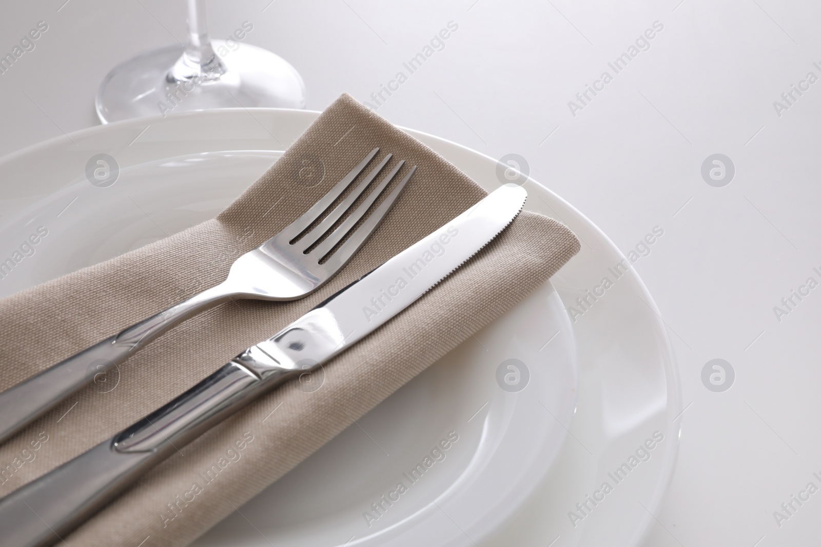Photo of Elegant cutlery with napkin on white table, closeup