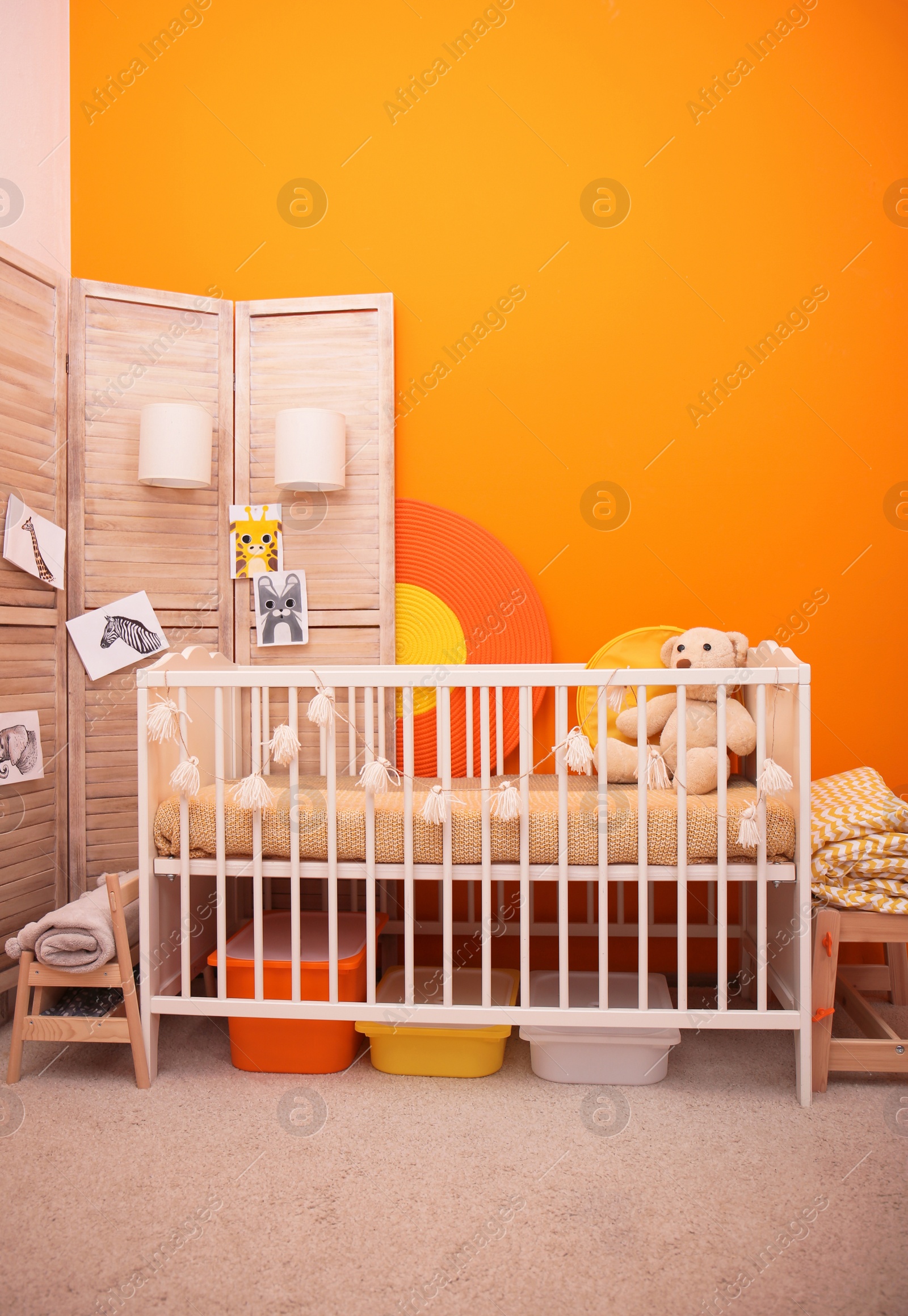 Photo of Baby room interior with crib near color wall