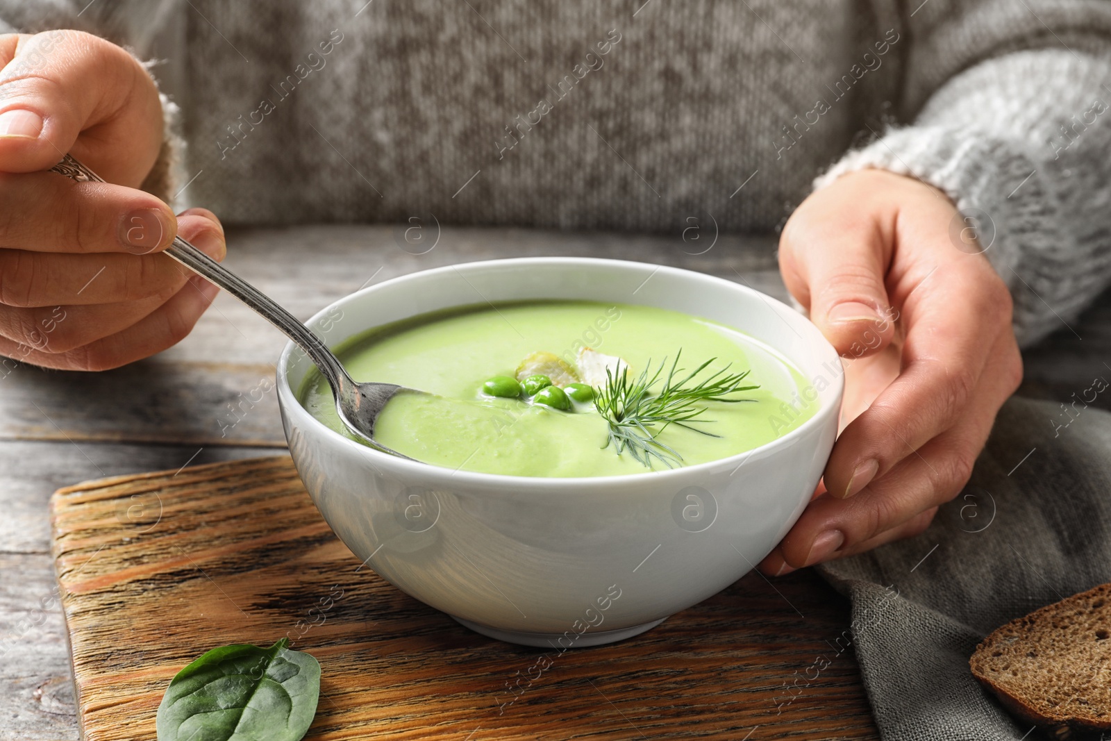 Photo of Woman eating fresh vegetable detox soup made of green peas at table, closeup