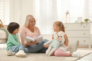 Photo of Happy grandmother and her grandchildren spending time together at home