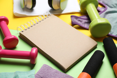 Composition with fitness equipment and notebook on color background