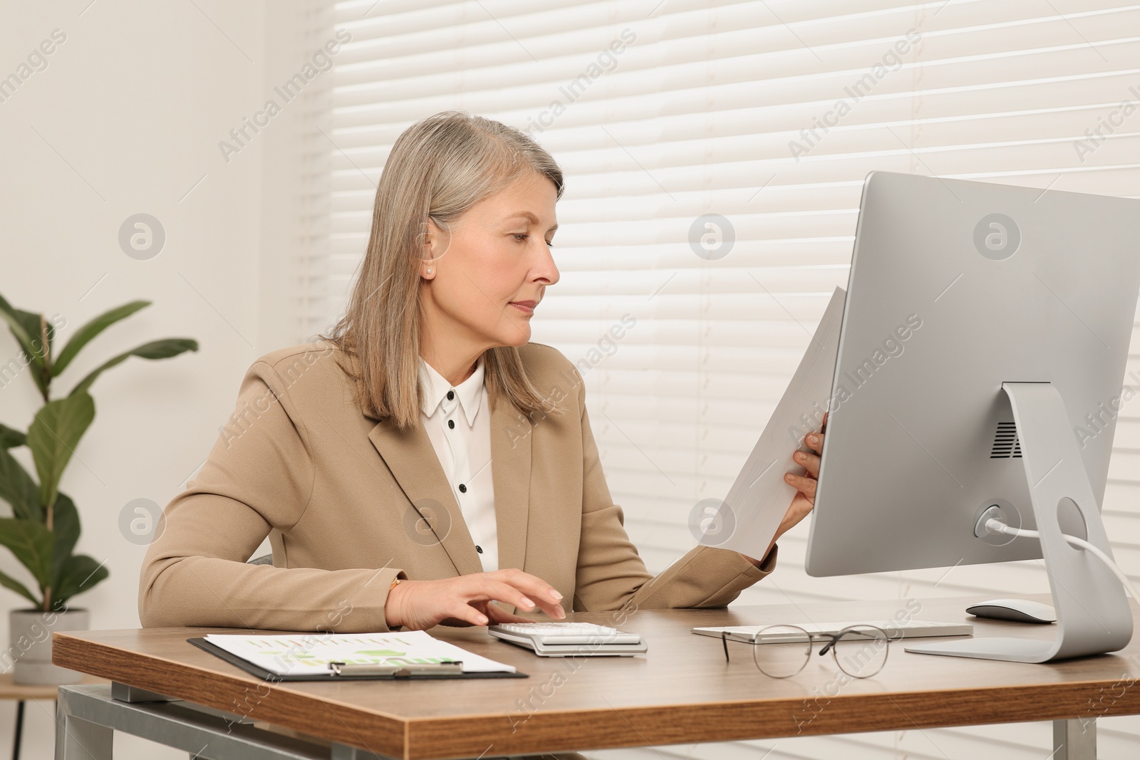 Photo of Senior accountant working at wooden desk in office