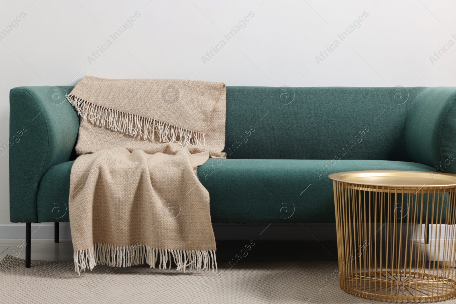 Photo of Comfortable sofa, blanket and side table in living room