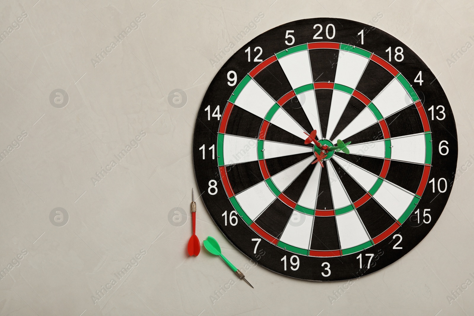 Photo of Dart board with color arrows on light stone background, top view. Space for text