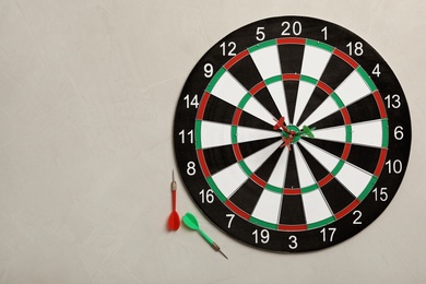 Dart board with color arrows on light stone background, top view. Space for text