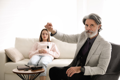 Photo of Psychotherapist using pendulum during hypnotherapy   session in office