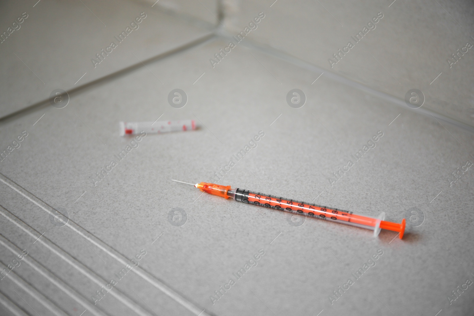 Photo of Disposable syringe with needle on tiled stairs indoors