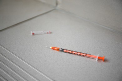 Photo of Disposable syringe with needle on tiled stairs indoors