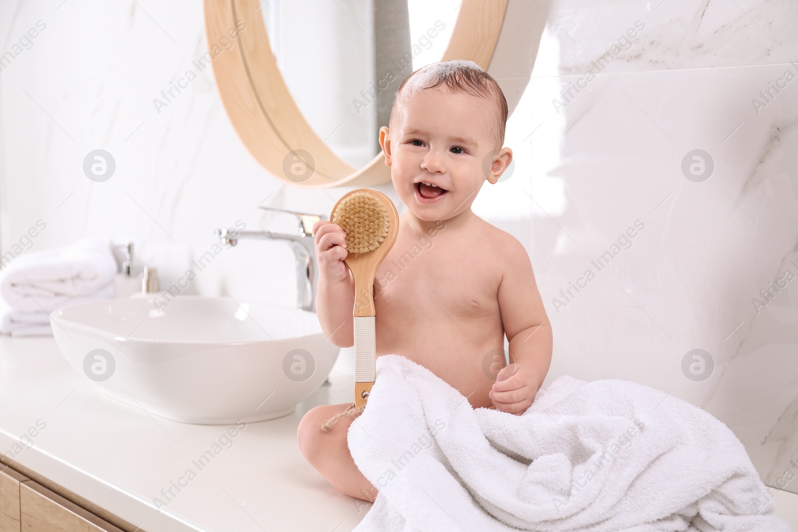 Photo of Cute little baby sitting on countertop in bathroom